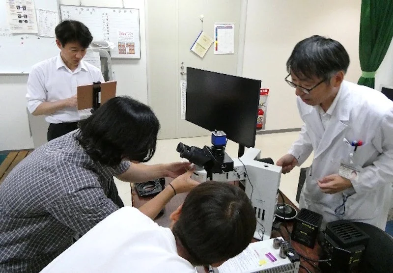 顕微鏡を操作しながら学ぶ参加者