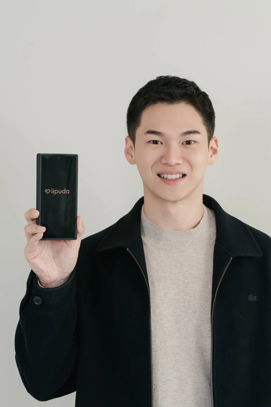 iipudaのロゴが表示されたスマートフォンを手にする男性