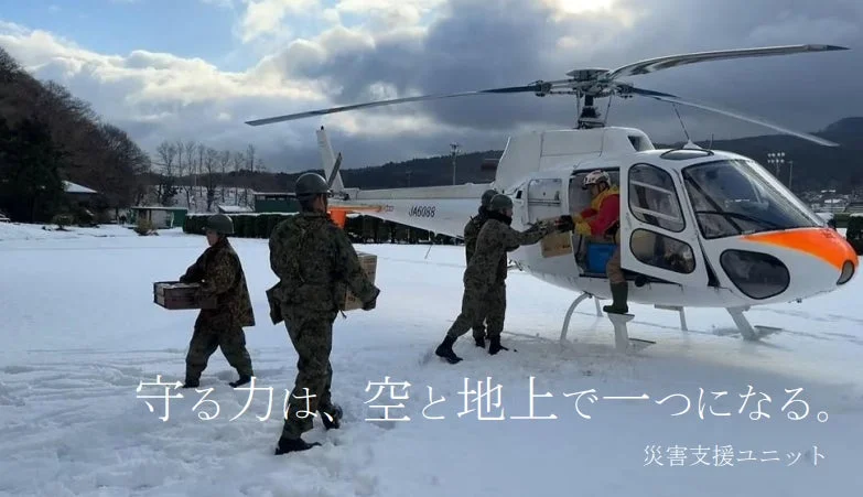 雪が積もる中でヘリコプターから物資を積み下ろす隊員たち