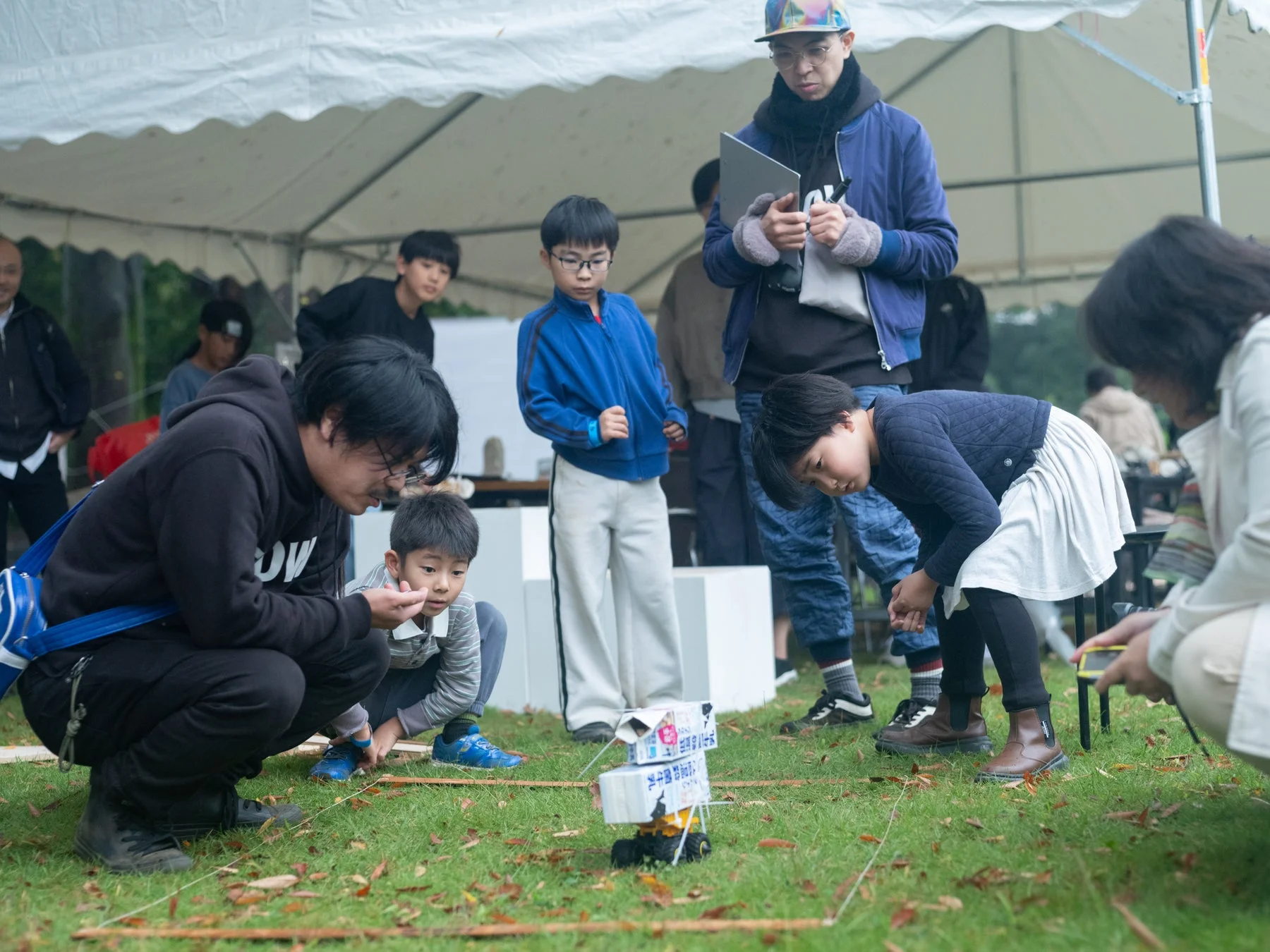屋外でロボットを見る大人と子供