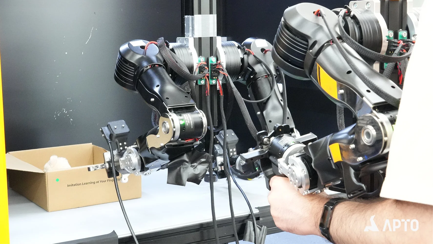 複雑なロボットアームが複数設置され、一人の人間がそのアームの一つを操作している様子