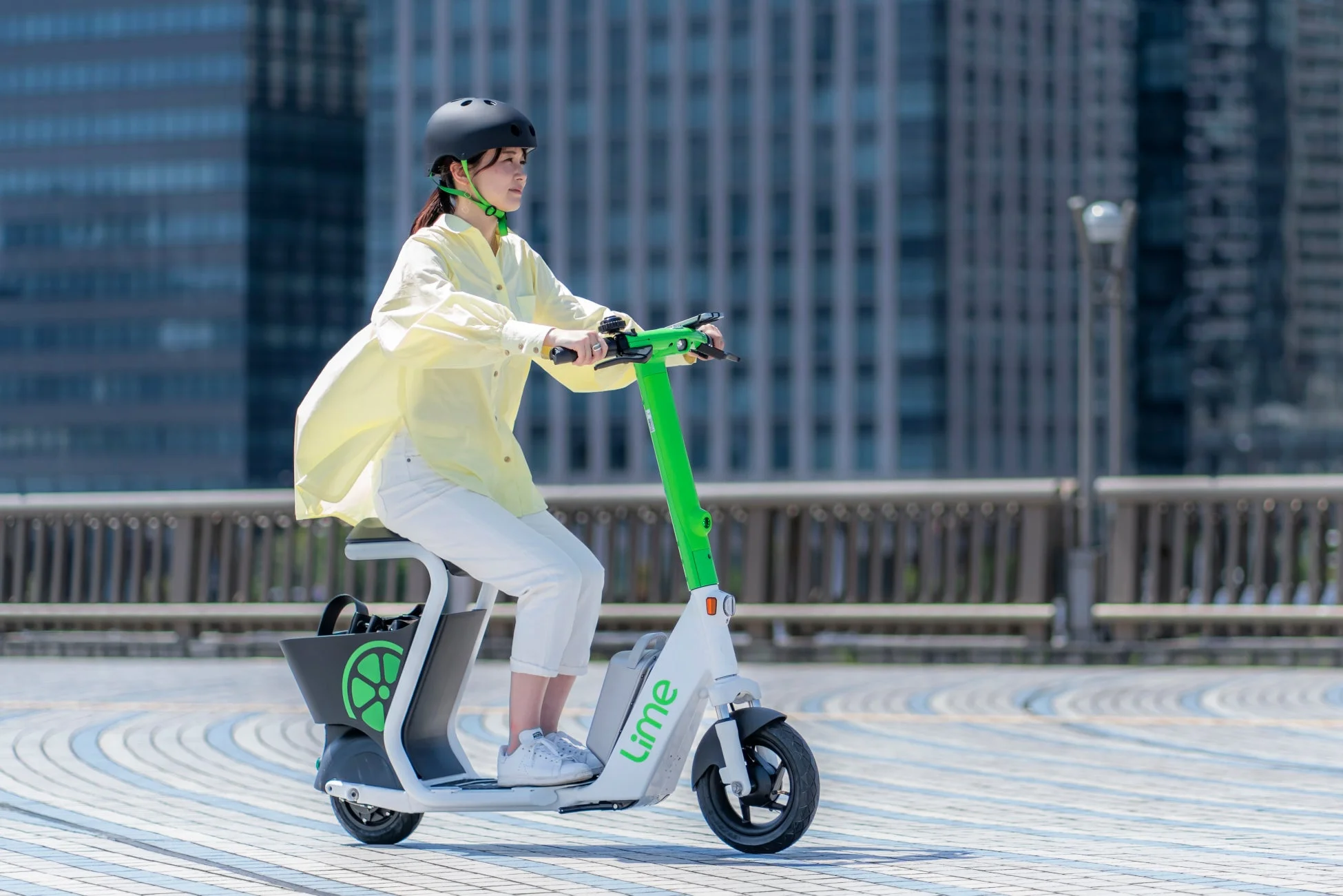 ヘルメットを着用した女性がLimeの電動キックボードに乗っている様子