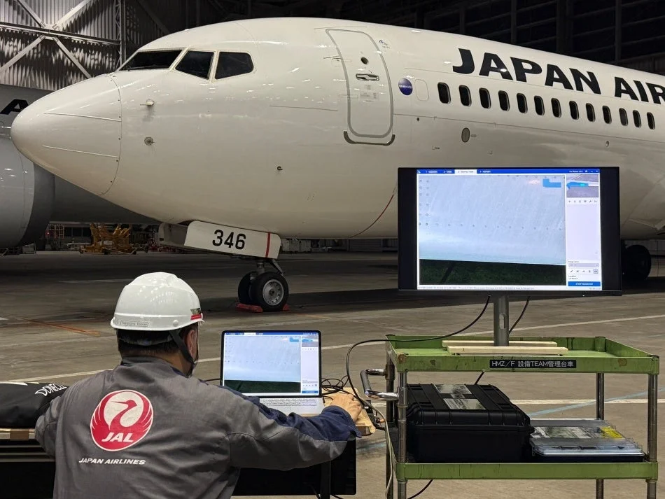 格納庫内でJAL機を点検する作業員とモニター